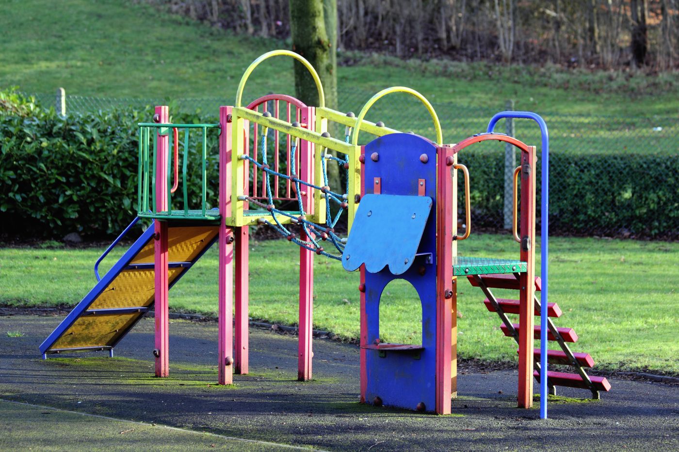 Buntes Klettergerüst mit Rutsche auf einer grünen Wiese im Freien