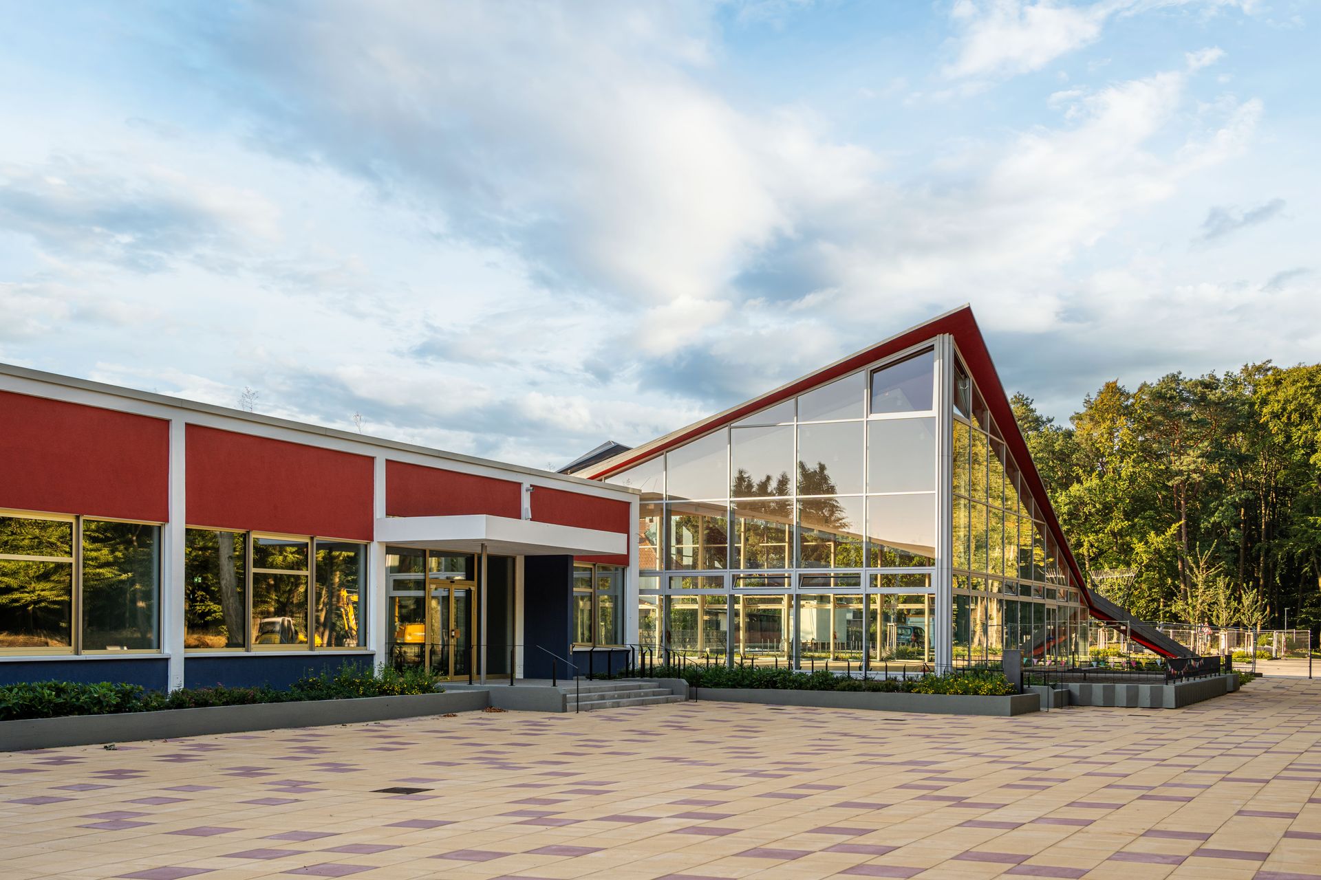 Helles, modernes Gebäude mit großer Glasfront und Terrasse im Grünen – Symbolbild für eine zeitgemäße Kindertagesstätte